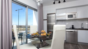 Una cocina moderna con comedor, que incluye una mesa de vidrio, sillas blancas y vistas al paisaje.