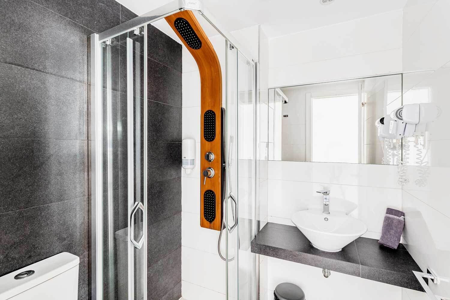 A modern bathroom with a glass shower enclosure, a white sink, and a mirror above the sink.