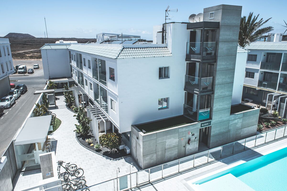 Un hotel moderno con piscina, un espacio exterior cubierto y una escalera que conduce a la entrada.
