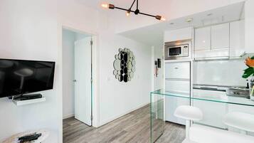 Una cocina moderna con gabinetes blancos, una mesa de comedor de vidrio y un microondas integrado.