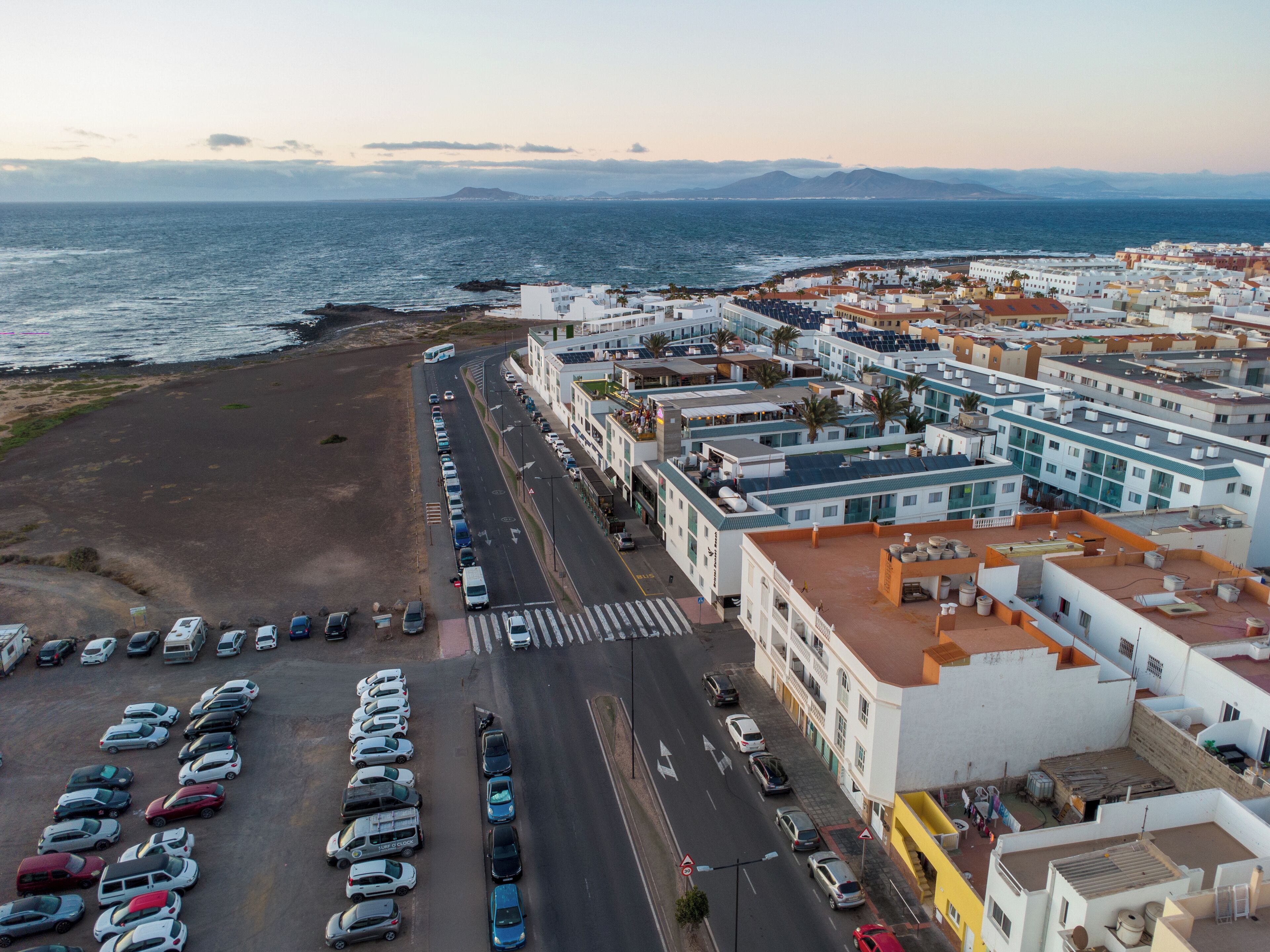 A coastal town with a parking lot, buildings, and a view of the sea.