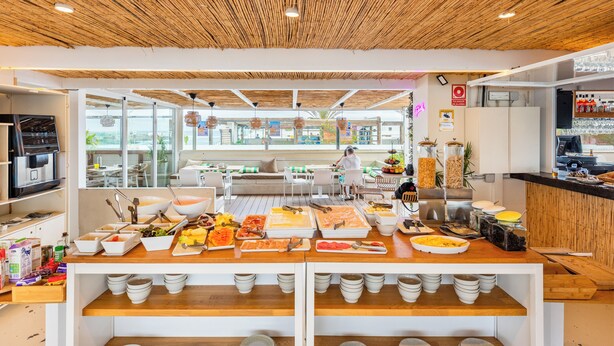 Montaje tipo buffet con diversos alimentos y una zona de estar con vistas al exterior.