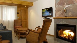 Una sala de estar acogedora con chimenea, muebles de madera y un televisor montado en la pared.