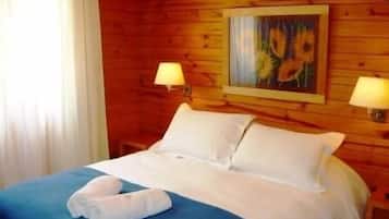 A wooden cabin-style room with a bed, two bedside lamps, and a painting on the wall.