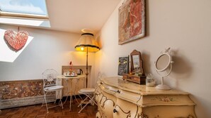 Ein gemütliches Zimmer mit Holzboden, einem weißen Stuhl, einem Tisch mit Lampe und einem Vintage-Schnäppchen mit Spiegel.