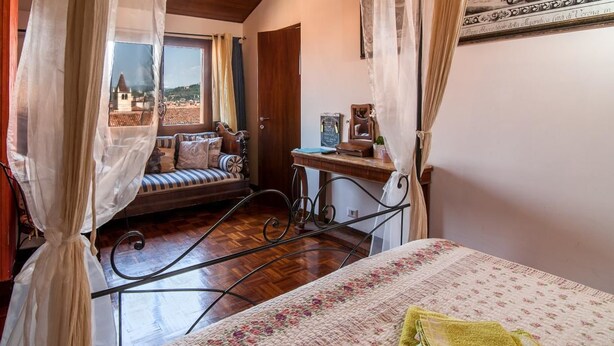 Ein Schlafzimmer mit Bett, Fensterbank und Blick auf eine Stadt.