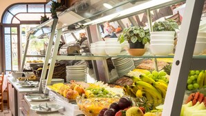 Un bufé con diversas frutas y verduras, entre ellas plátanos, manzanas y naranjas.