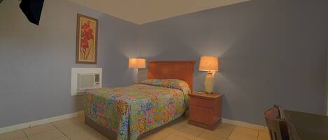 Une chambre à coucher avec un lit, des tables de chevet, une lampe, un radiateur et un tableau au mur.