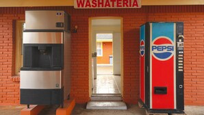 Un baño con máquina expendedora de Pepsi y un refrigerador.
