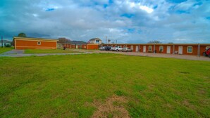 Un edificio con estacionamiento y un campo verde al frente.