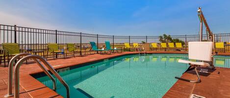 A pool area with a clear blue pool, a metal ladder, and multiple lounge chairs.
