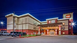 A Best Western Plus hotel with a modern facade, a fire lane, and a parking lot with SUVs.