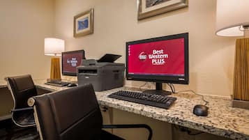 A hotel workspace with two monitors, a printer, a keyboard, and a mouse.