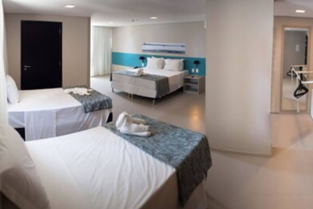 A hotel room with two beds, a desk, and a chair.