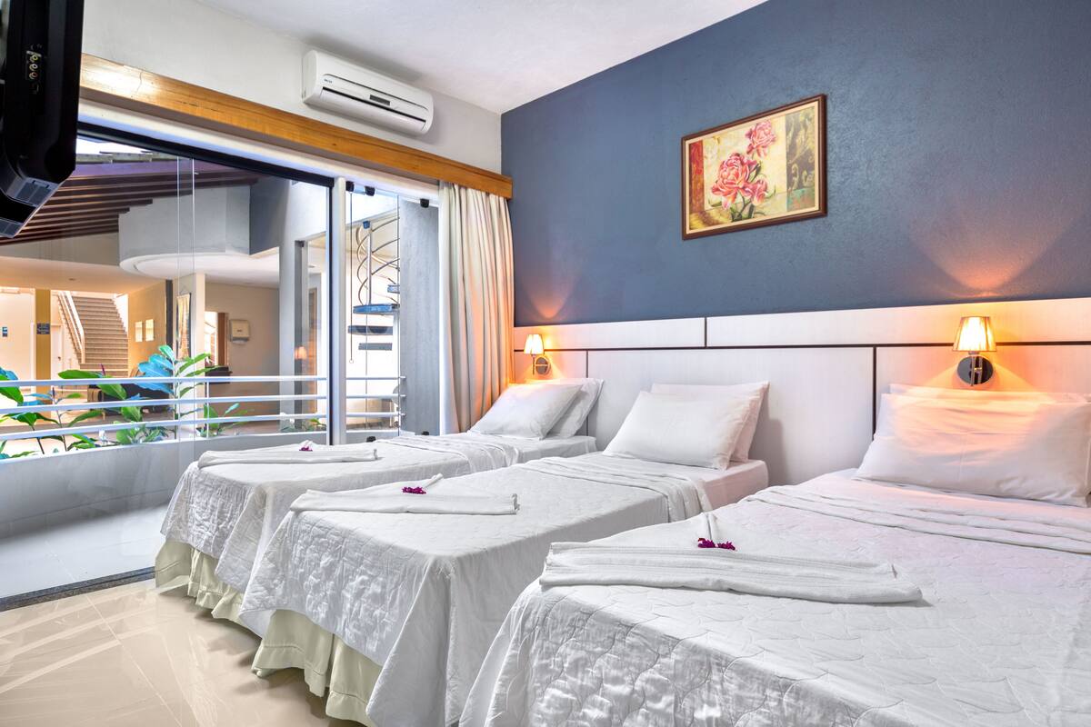 Habitación de hotel con dos camas, un ventanal con vista a una piscina y un cuadro en la pared.