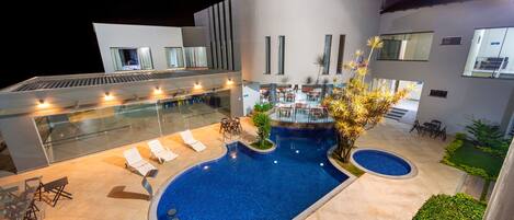 A modern hotel with a swimming pool, outdoor seating, and a well-lit terrace.