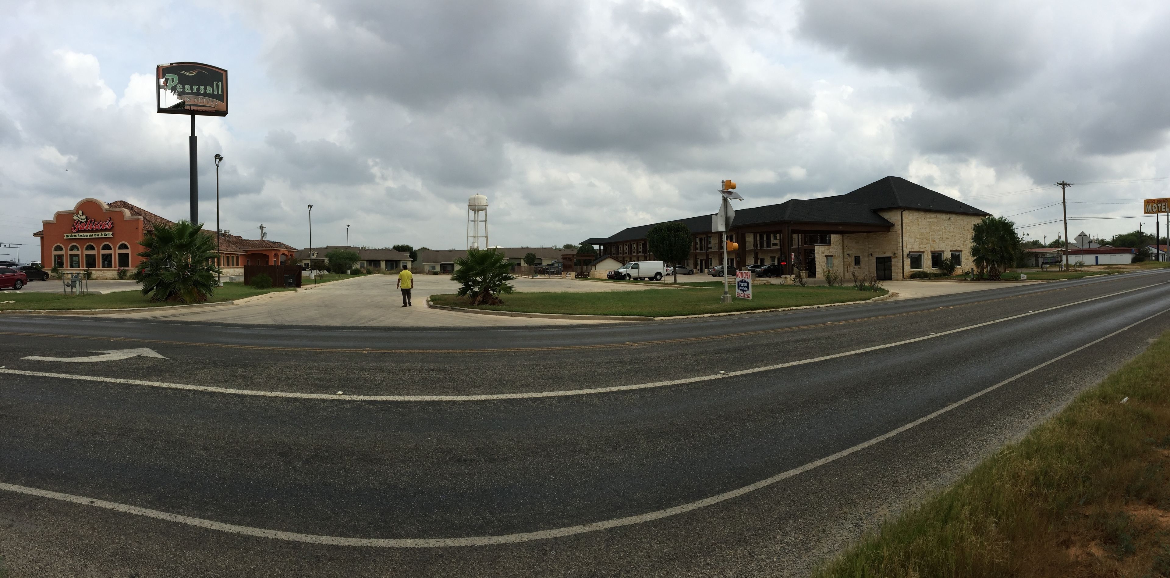 Una intersección de calles con un restaurante Pearsall y un motel al fondo.