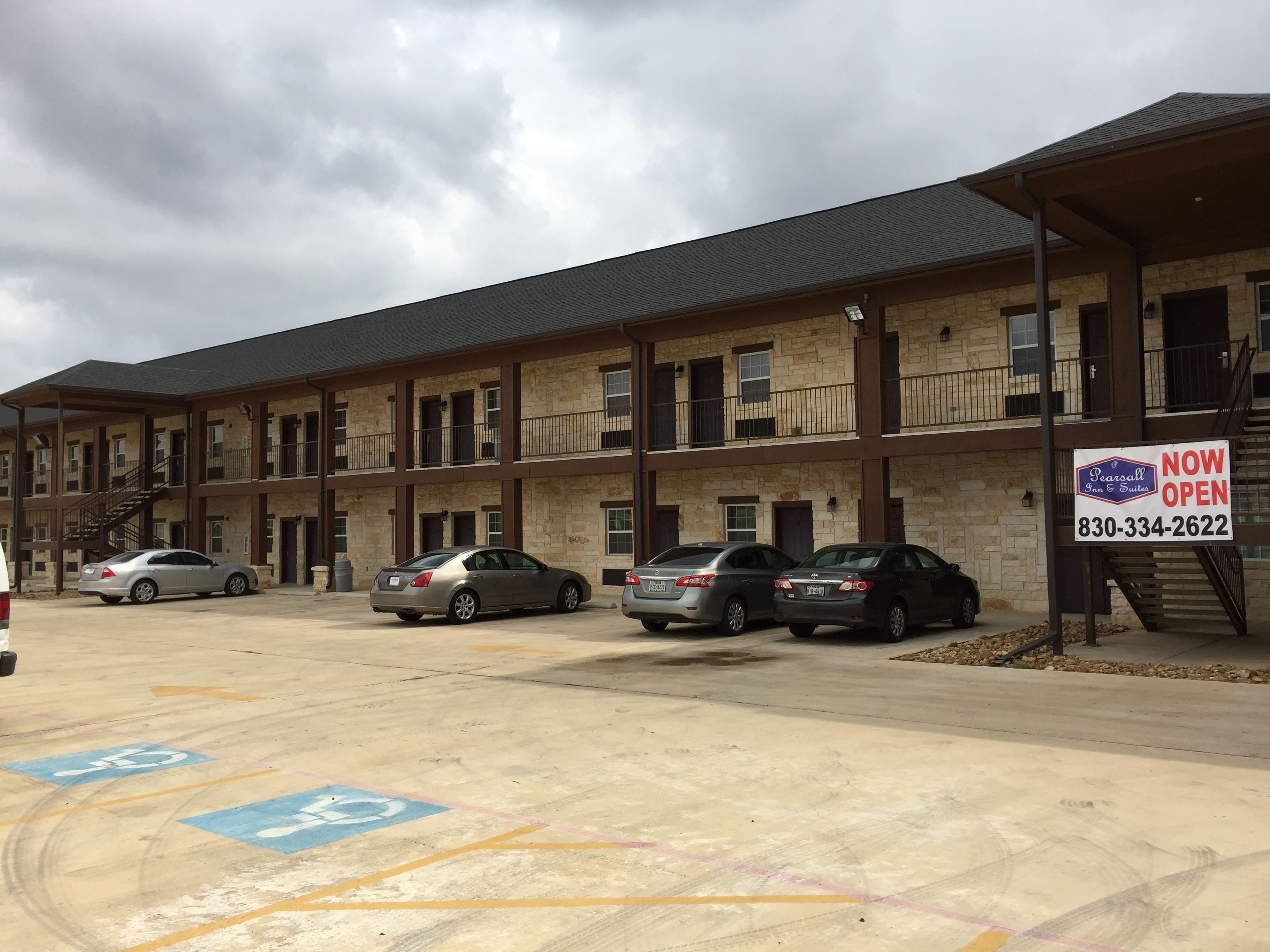 A multi-story motel with a stone facade, multiple balconies, and a parking lot with handicapped parking spaces.