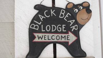Un letrero con forma de oso negro que dice "BLACK BEAR LODGE" y una flecha de "BIENVENIDA".