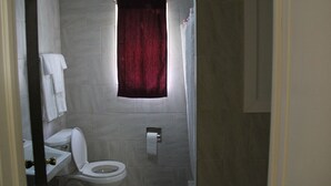 A bathroom with a toilet, sink, and shower curtain. - Pleasant Hill Motel (Middletown)
