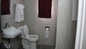 A bathroom with a toilet, sink, and towel rack. - Pleasant Hill Motel (Middletown)