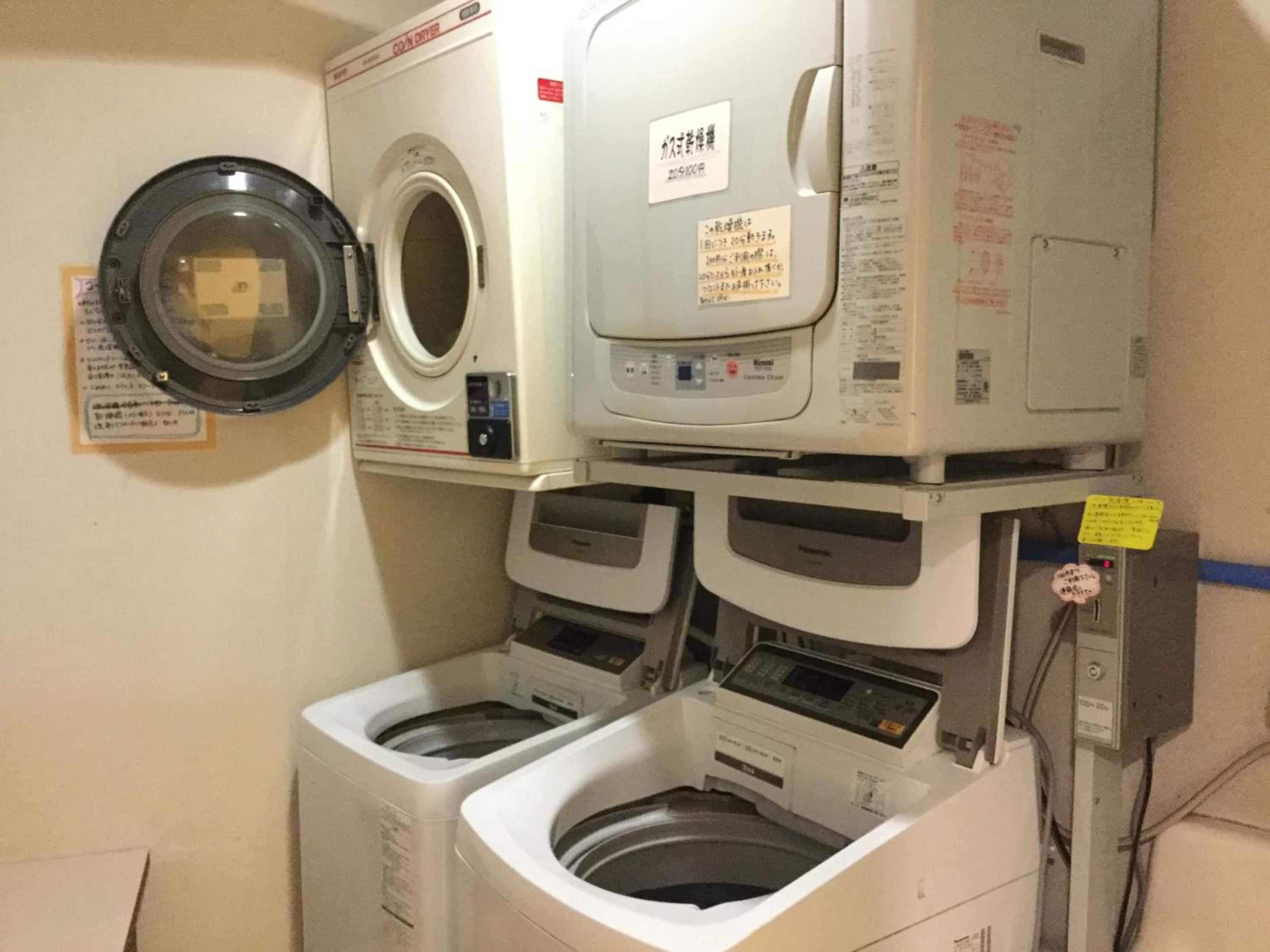 A laundry room with a front-loading washing machine, a top-loading dryer, and a stacked washer and dryer unit.