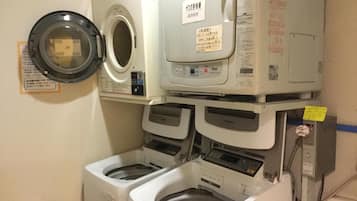 A laundry room with a front-loading washing machine, a top-loading dryer, and a stacked washer and dryer unit.