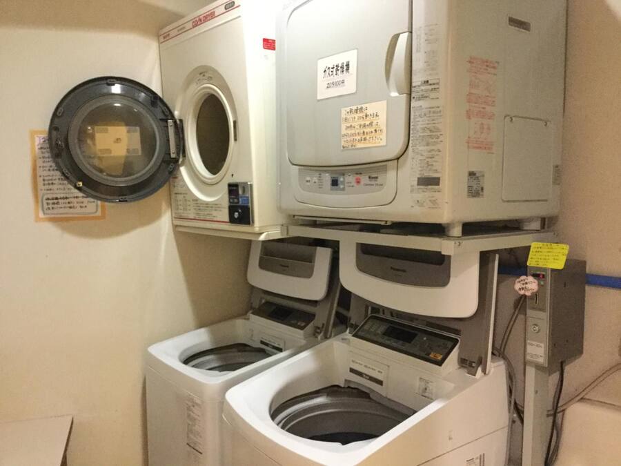 A laundry room with a front-loading washing machine, a top-loading dryer, and a stacked washer and dryer unit.