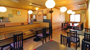 Ein Restaurant mit mehreren Tischen, Stühlen, einer Theke und hängenden Lampen.