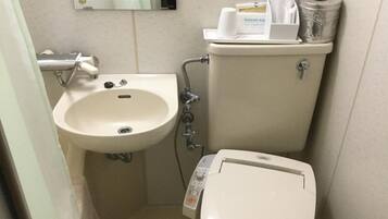 A small bathroom with a white sink, toilet, and a mirror above the sink.