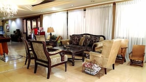 A spacious living room with a sofa, armchairs, a coffee table, and a dining area with a table and chairs. - Victoria Hotel (San Pedro Sula)