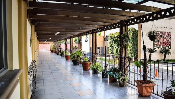 A covered corridor with tiled flooring, potted plants, and a metal railing. - Victoria Hotel (San Pedro Sula)