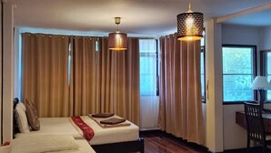 Habitación de hotel con una cama grande, dos mesitas de noche, un escritorio con una silla y una ventana con cortinas.