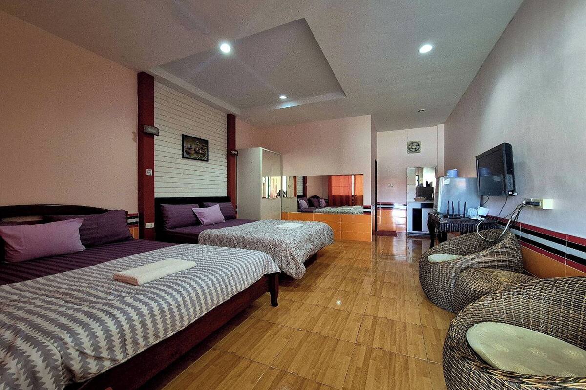 A hotel room with two beds, a TV, a desk, and a seating area.