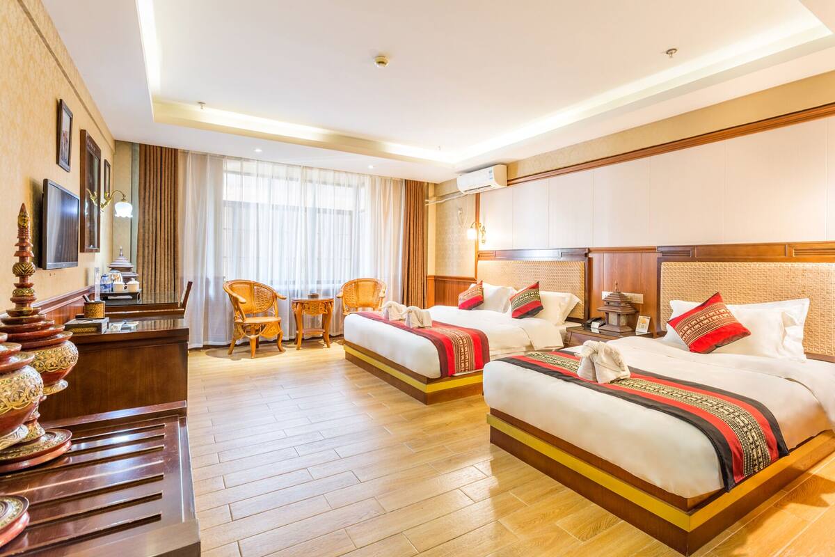 A hotel room with two beds, a desk, and a chair.
