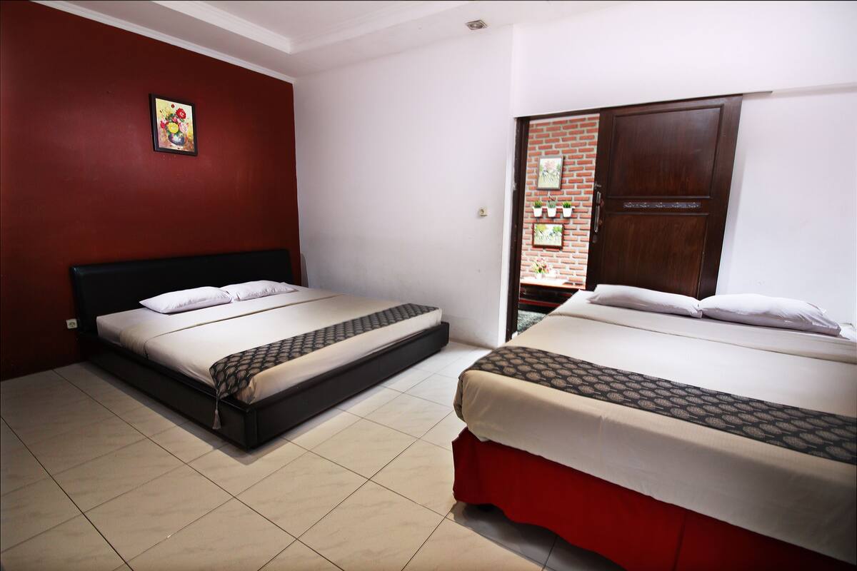 Two beds with red and black headboards in a room with a red wall and a white ceiling.