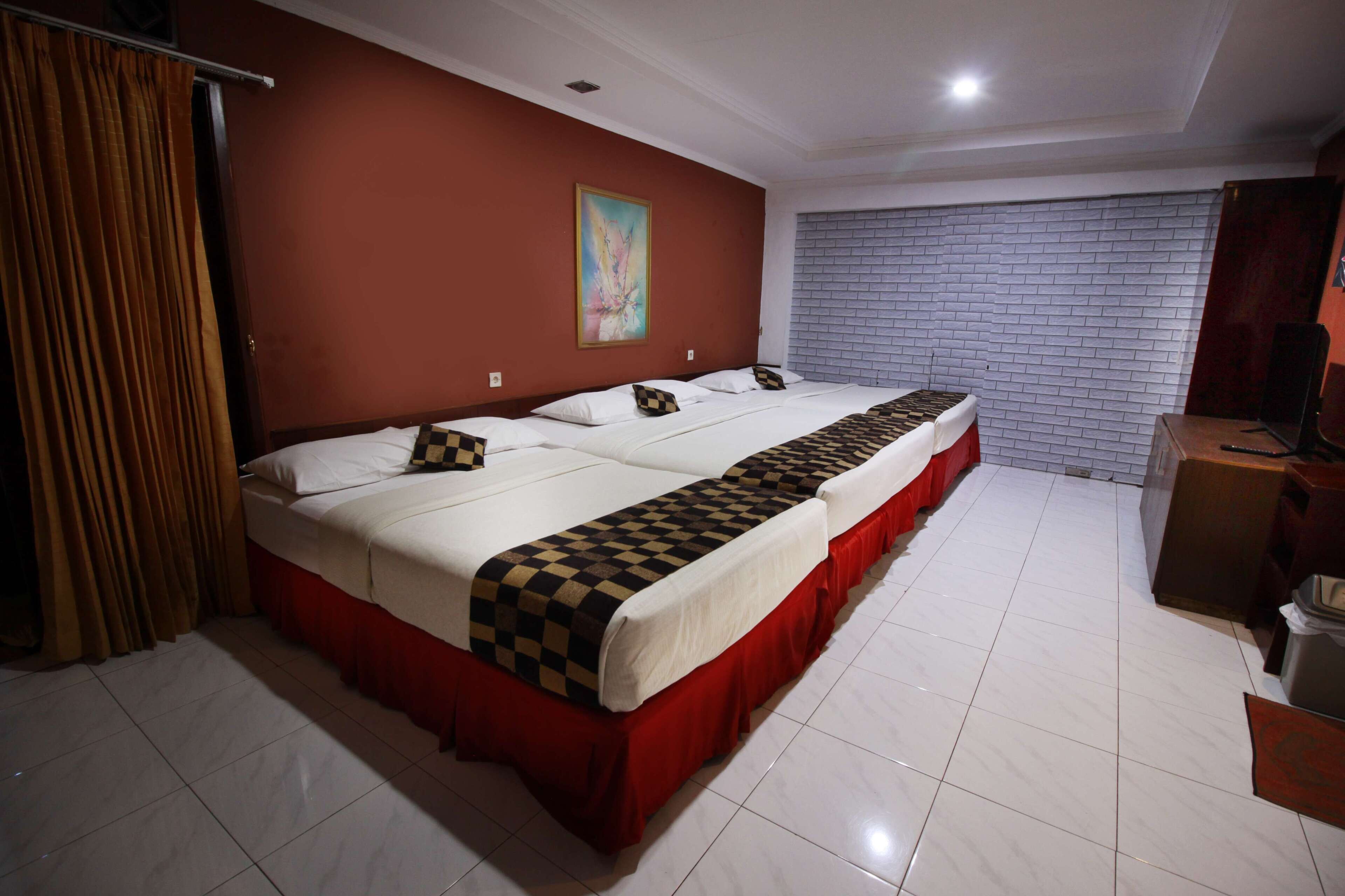 Habitación de hotel con una cama grande, cortinas rojas, pared de ladrillo blanco y un cuadro en la pared.