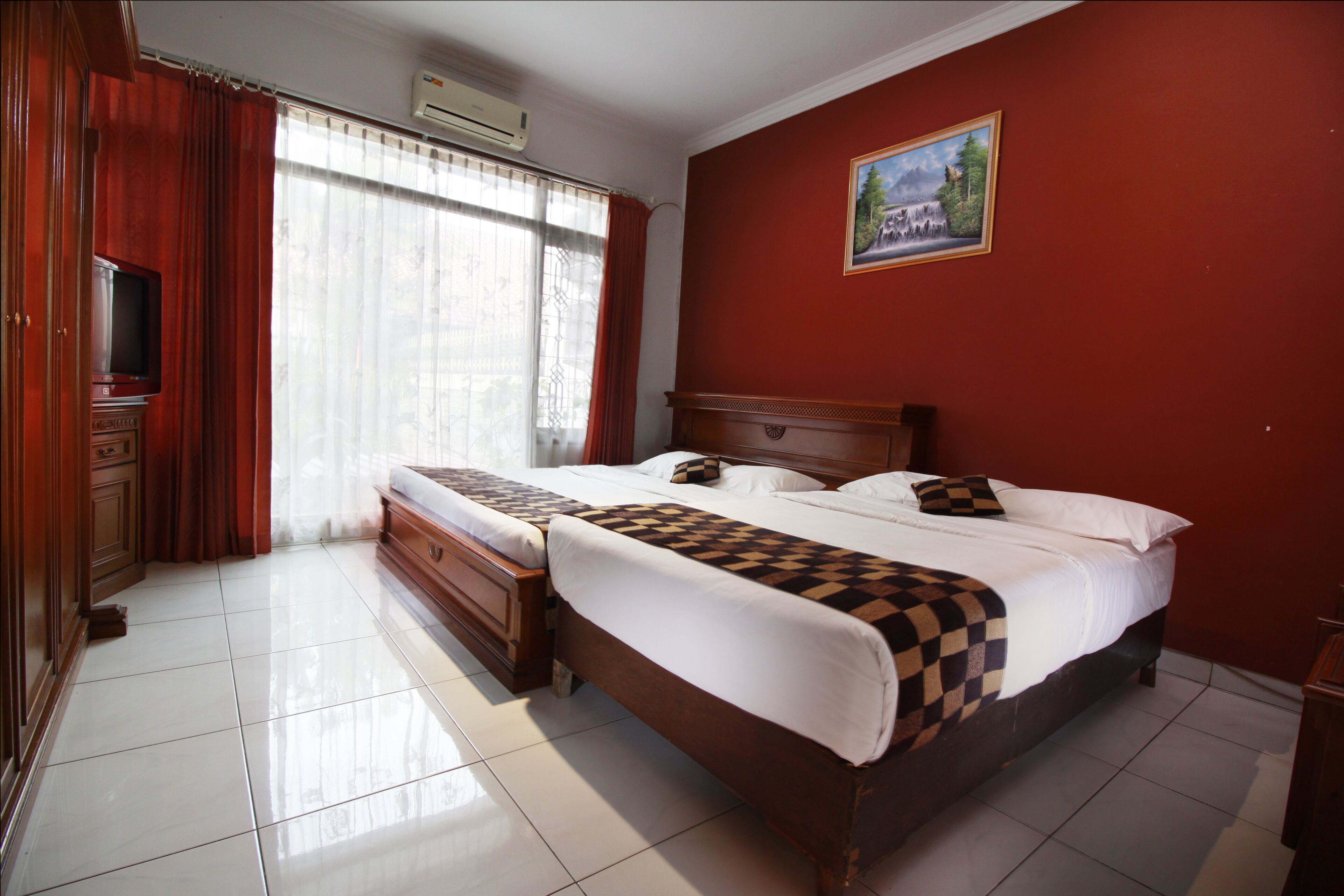 A hotel room with a large bed, a television, and a painting on the wall.
