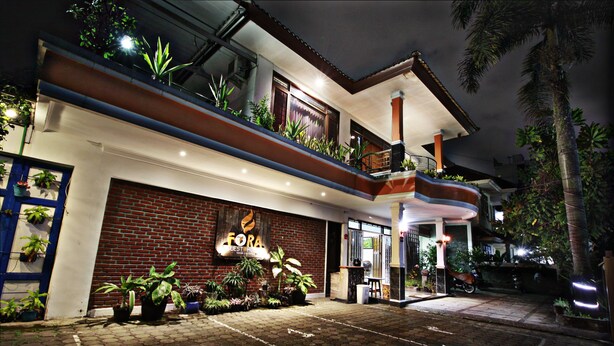 A two-story building with a brick facade, a balcony with plants, and a sign that reads "Fora Guesthouse." - Fora Guest House Taman Lingkar (Bandung)