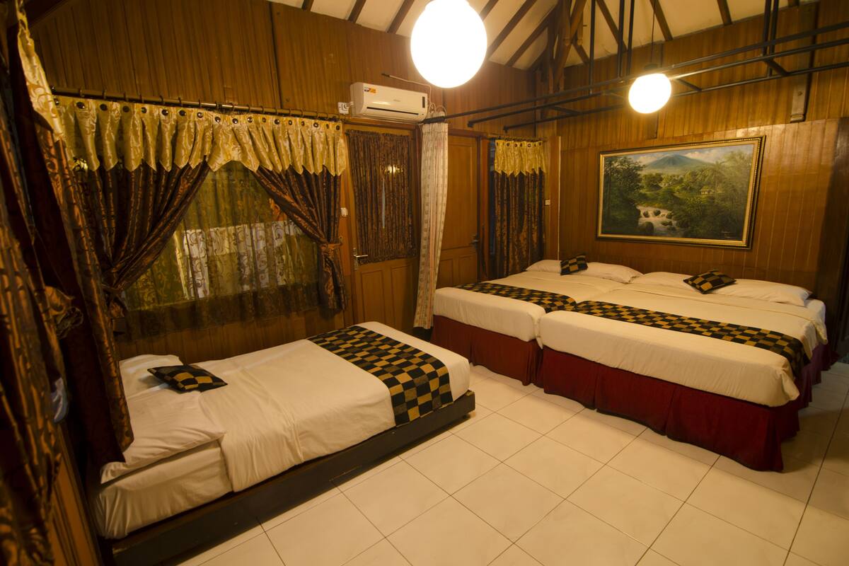 A hotel room with two beds, a painting on the wall, and an air conditioning unit.