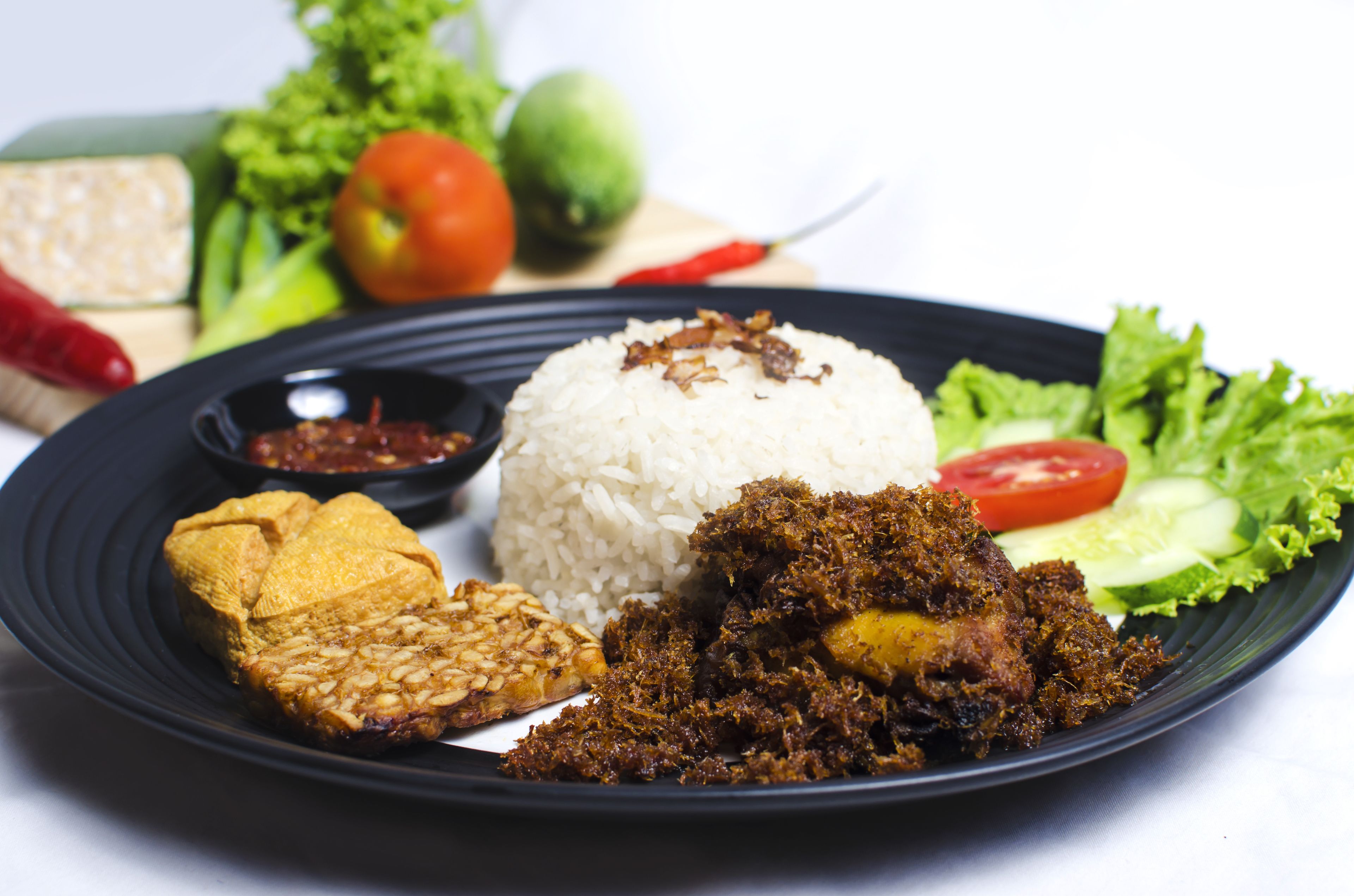 Une assiette de nourriture composée de riz, de poulet frit et de légumes.