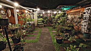 A well-lit indoor garden with various potted plants arranged along a central pathway. - Fora Guest House Taman Lingkar (Bandung)