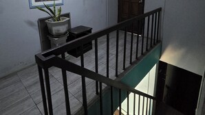 A staircase with a metal railing, a door, a wall-mounted light switch, and a framed picture. - Malai Place Lampang (Lampang)