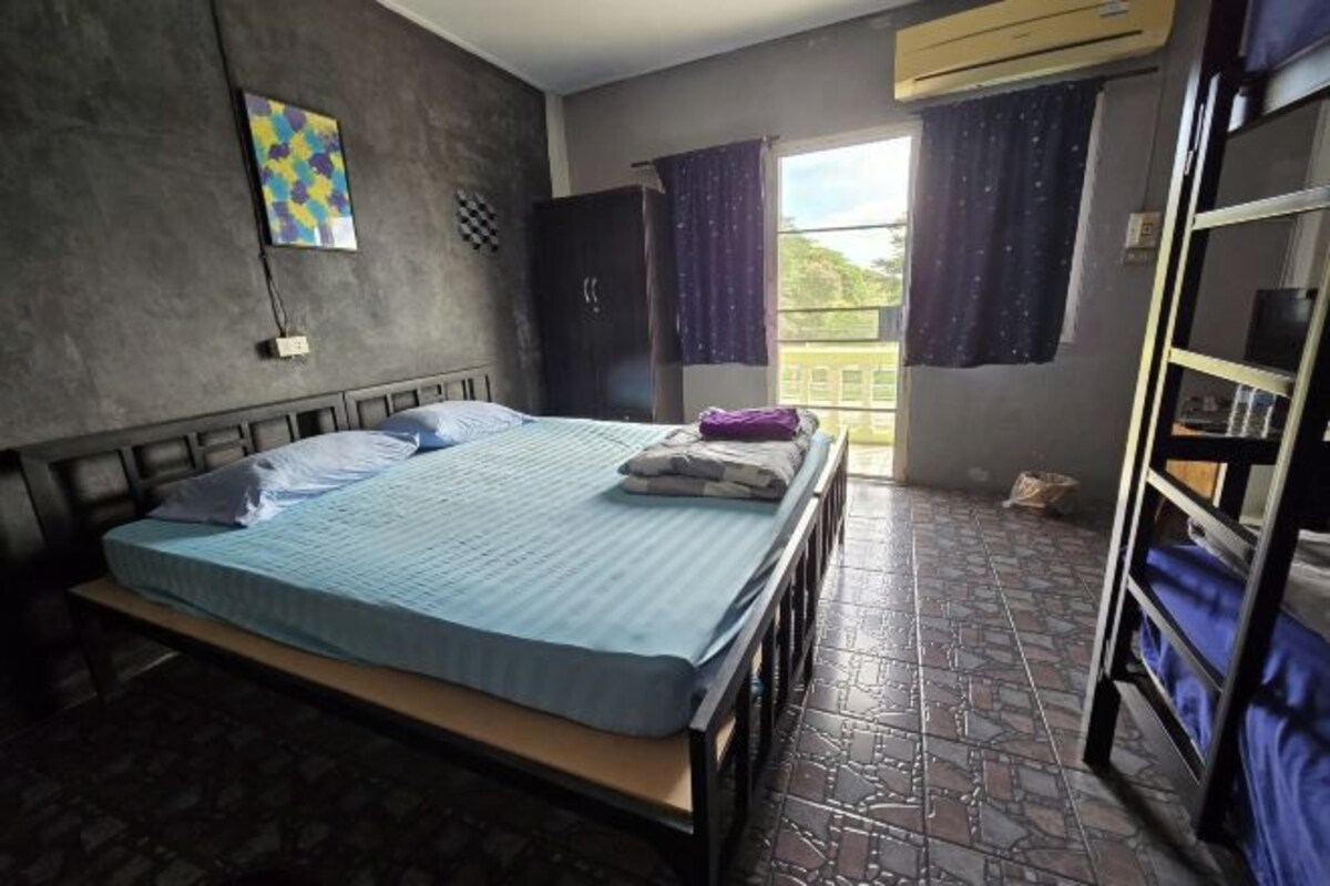 A bedroom with a bed, a wardrobe, a window with curtains, and a balcony.