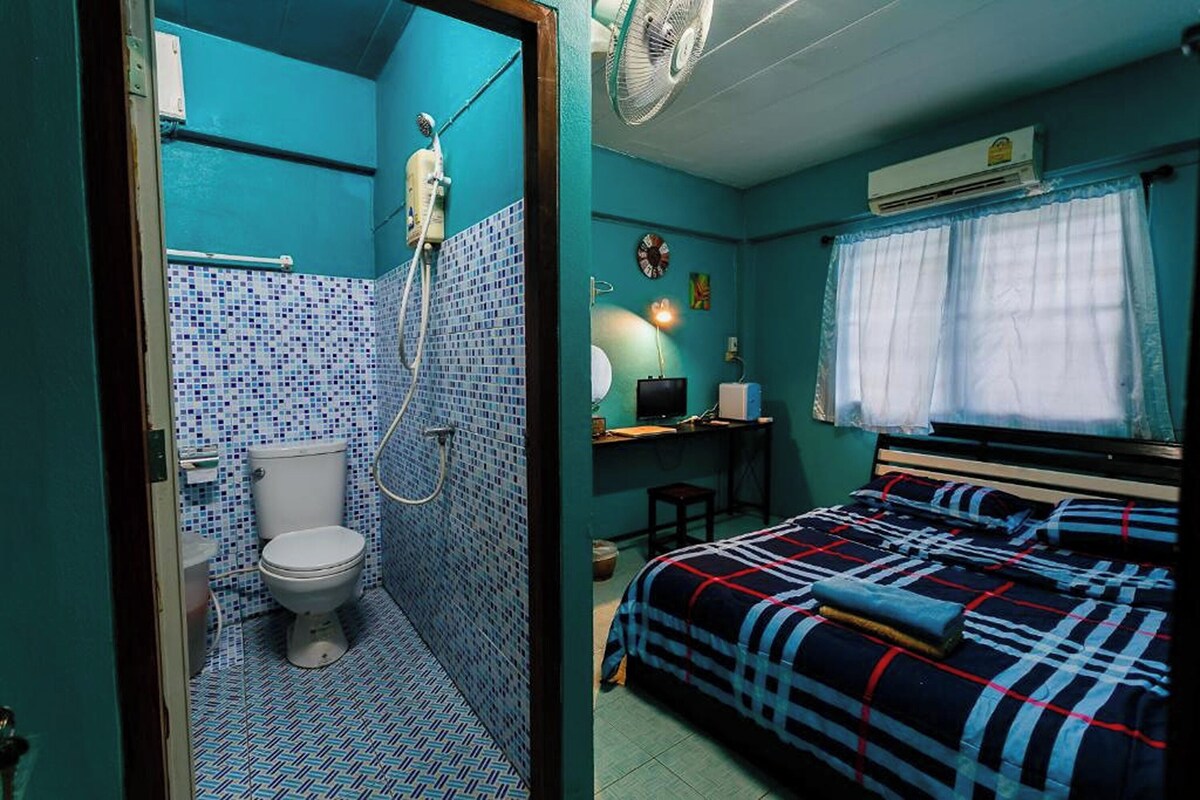 A compact room with a toilet, shower, and a bed with a blanket.