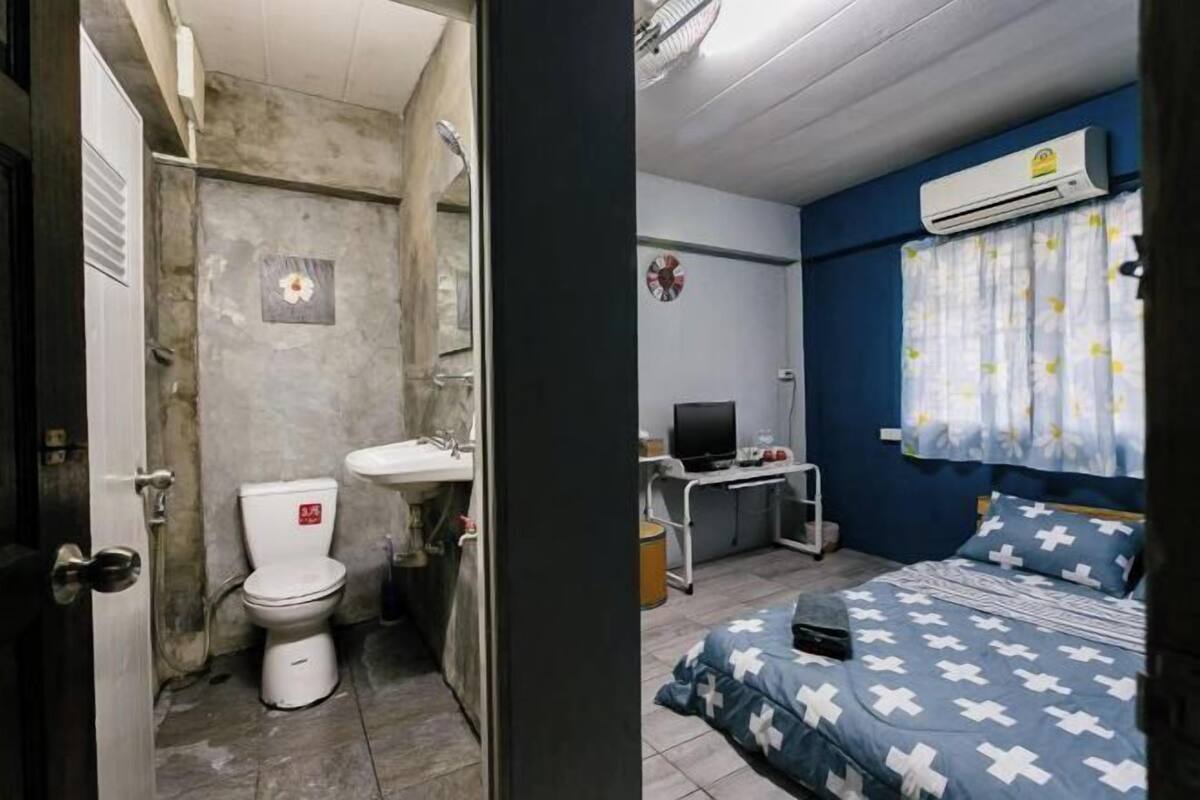 A small room with a toilet, sink, and a bed with a patterned bedspread.