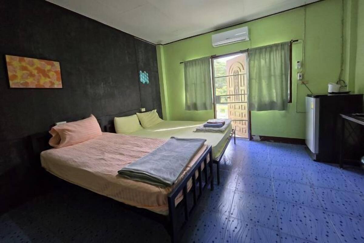 A room with a bed, a desk, and a window with curtains.