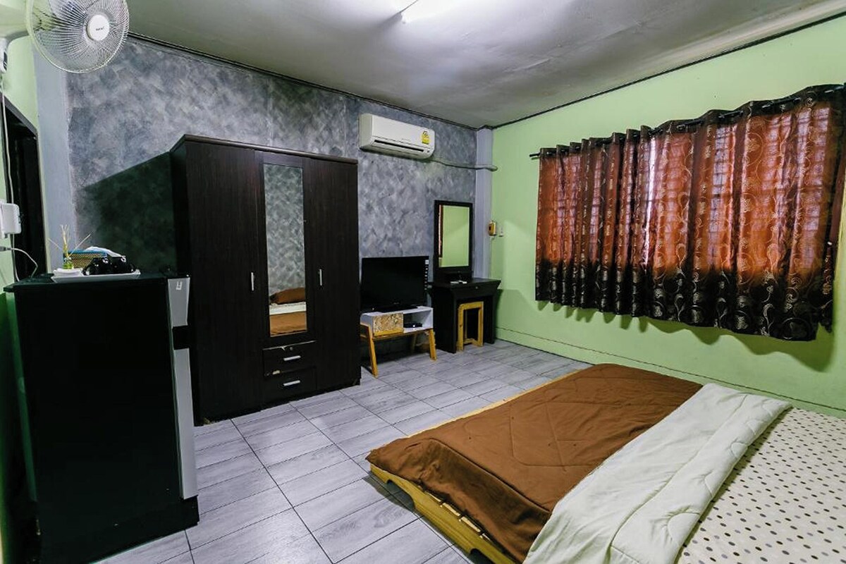 A bedroom with a bed, a wardrobe, a desk, a chair, and a mirror.
