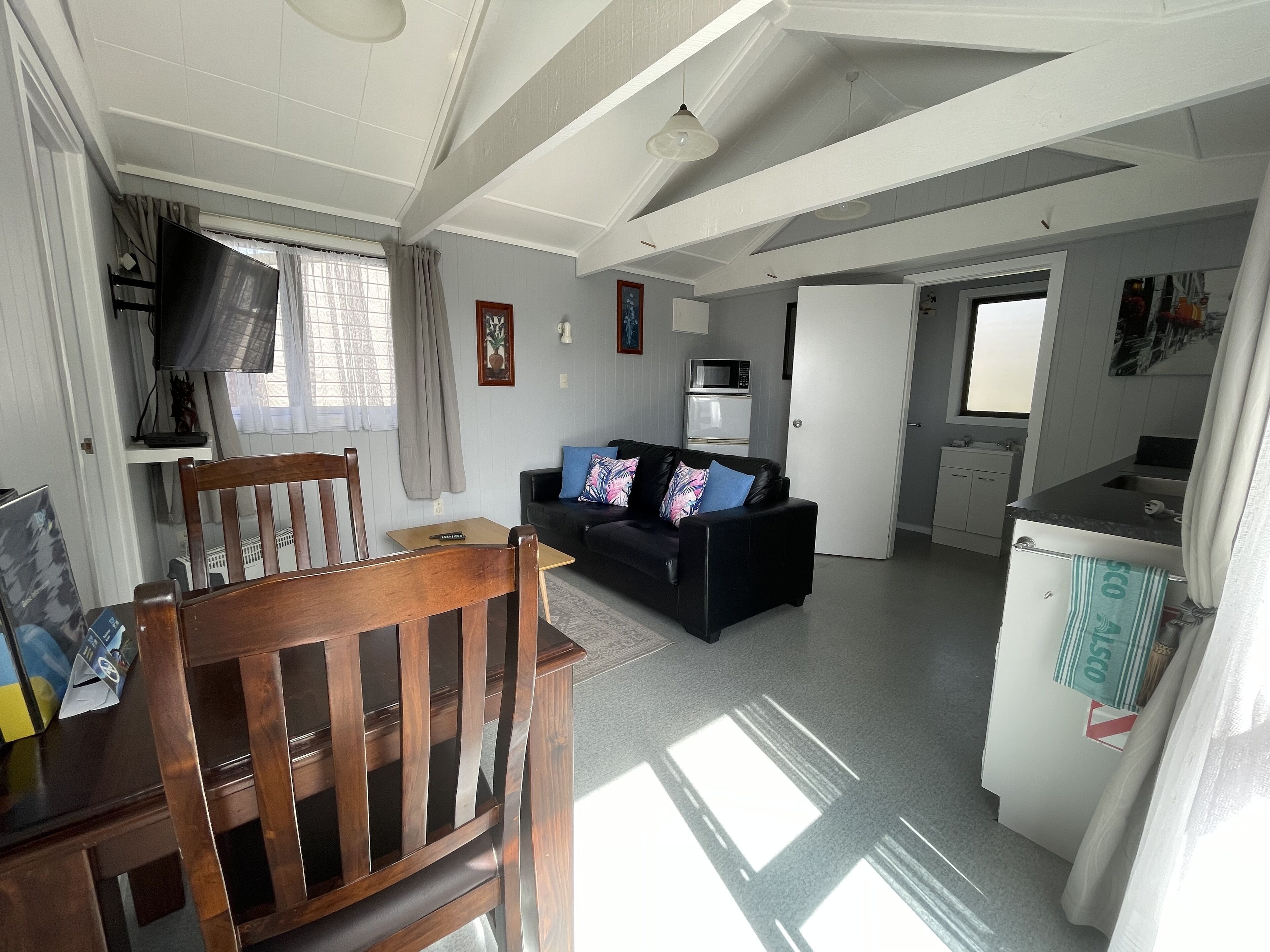 Un espacio habitable compacto con comedor, sofá, kitchenette y televisor.
