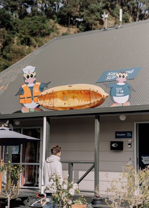 A building with a reception area, a sign for 'Reception', and a person standing near the entrance. - Motutere Bay Top 10 Holiday Park (Motutere)
